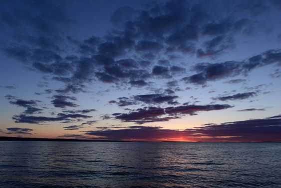 Flash of a bright red sunset on the horizon in the sky above the lake