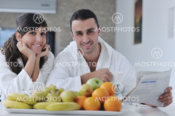 Happy couple reading the newspaper in the kitchen at breakfast