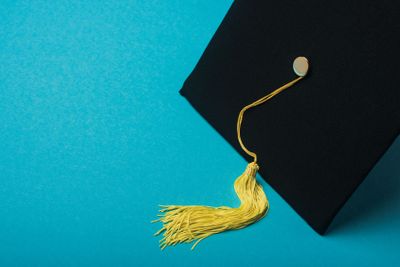 Graduation cap with yellow tassel on blue background