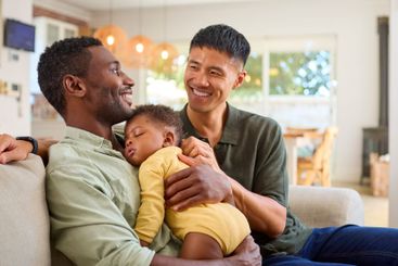 Same Sex Male Couple Or Friends Cuddling Sleeping Baby...