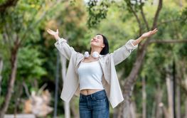 An asian woman is standing with her arms raised,...