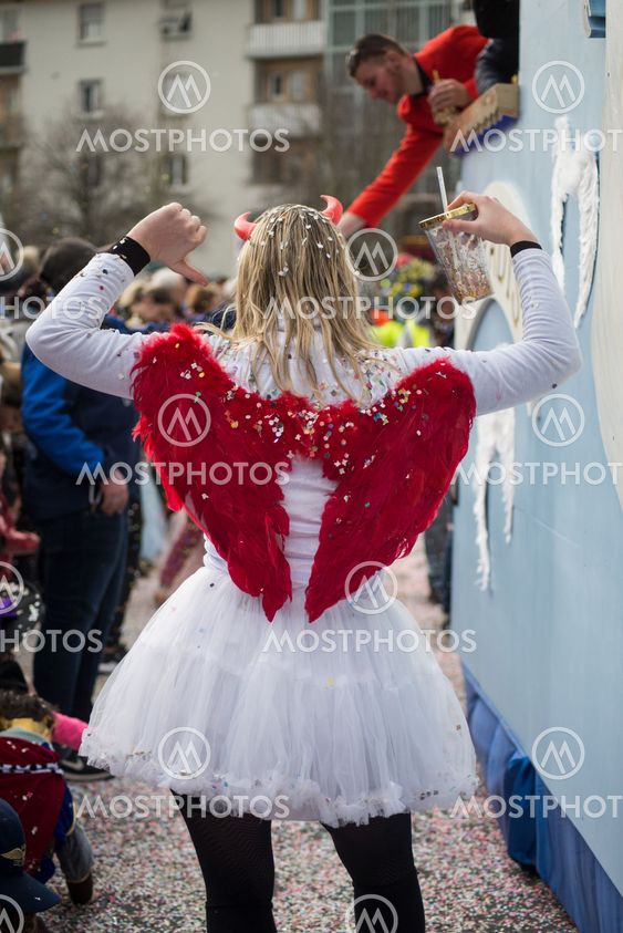 girl parading in the street with angel costume and red...
