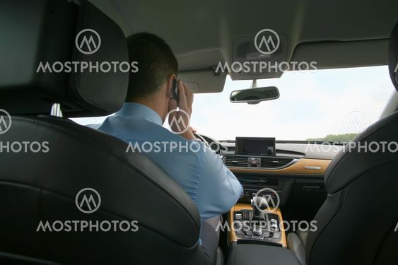 man speaks by phone in car