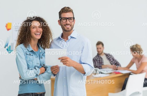 Happy designers using digital tablet smiling at camera