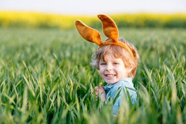 little kid boy having fun with traditional Easter egg hunt