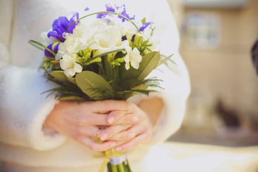Bridal bouquet held by a bride in a white sweater...