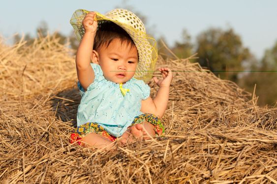 Baby of Asia sits on straw