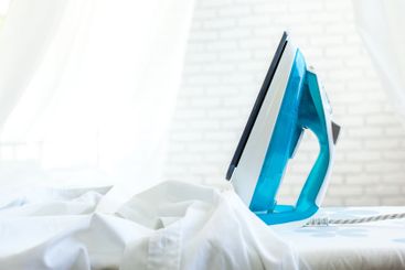 Iron on ironing board on light home interior background