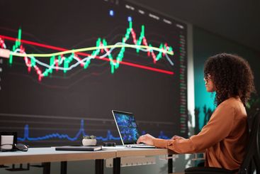 Female Stock Analyst Analyzing Data on Computer Screens