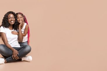 Happy mother and her little daughter cuddling over...