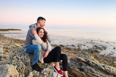 Young couple at rocky seacoast in sunset