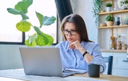 Middle-aged serious woman working at computer laptop in...