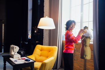 A young laughing African stands next to a dressmaker...
