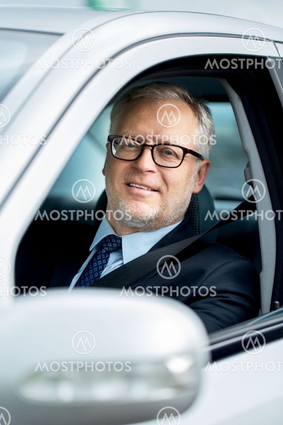 happy senior businessman driving car