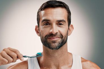 Smile, portrait and man brushing teeth on studio...