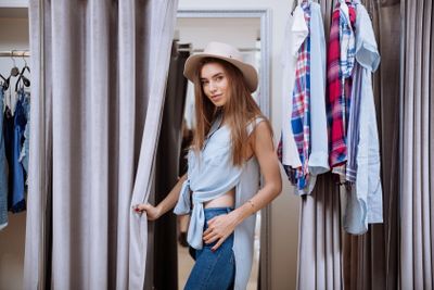 Woman trying on clothes in fitting room of clothing shop
