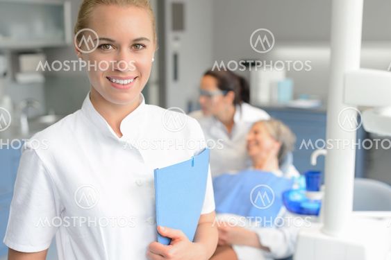 Dental assistant smiling dentist with patient
