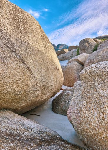 Rocks, sandy and beach by blue sky with clouds, scenic...