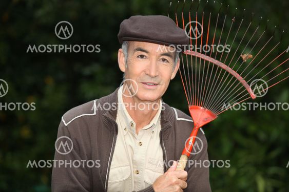 65 years old man wearing brown clothes and holding a rake