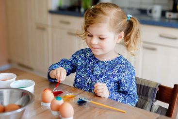 Excited little toddler girl coloring eggs for Easter....
