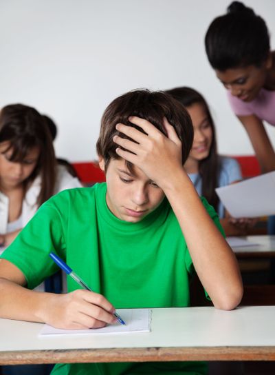 Sad Teenage Boy Writing Paper At Desk