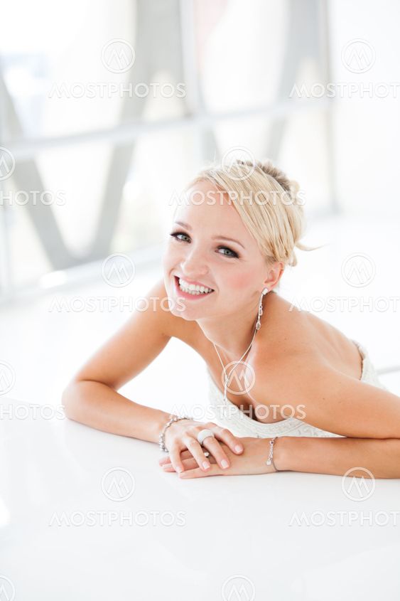Smiling beautiful blond bride sitting at a table