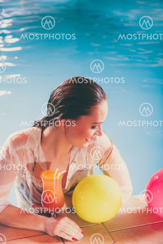 Happy woman with balloons and cocktail at poolside