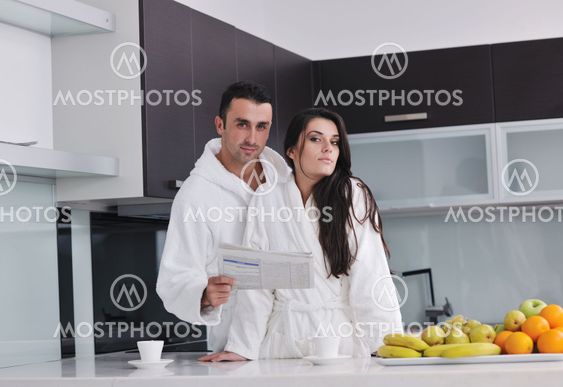 Happy couple reading the newspaper in the kitchen at breakfast