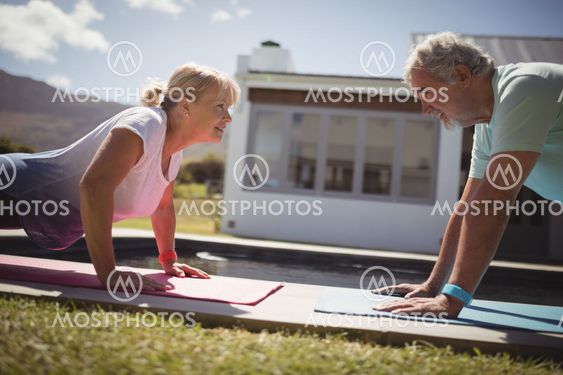 Senior couple doing push-up near swimming pool