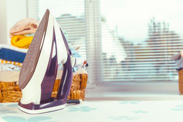 Iron on ironing board on light home interior background