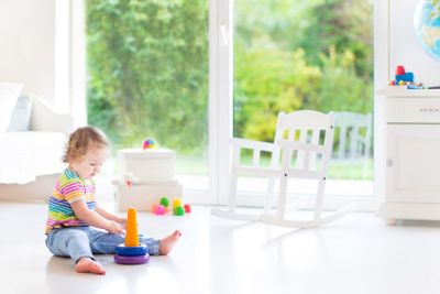 Cute toddler girl playing with a pyramid toy in a white...