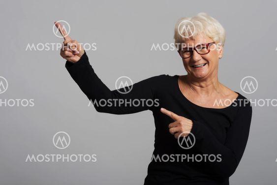 An old happy lady pointing on a copy space.