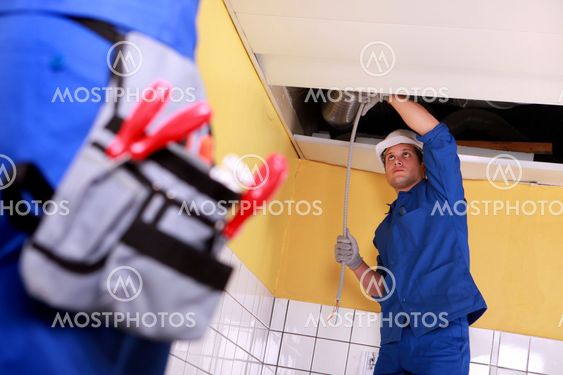 Two electrician working on ceiling electrics