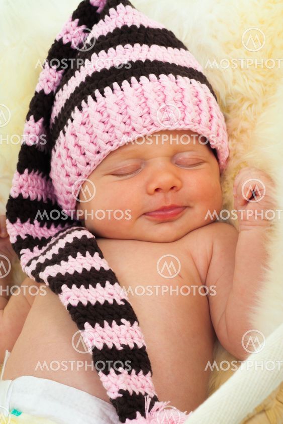 infant sleeping on a white sheepskin in a wicker basket.