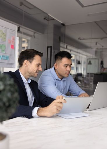 Two diverse male business colleagues working together at...