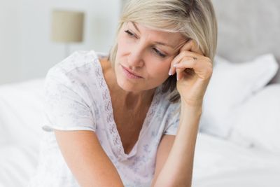 Tensed mature woman sitting in bed