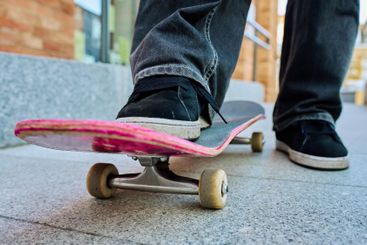Skateboarder riding on pink skateboard at city street