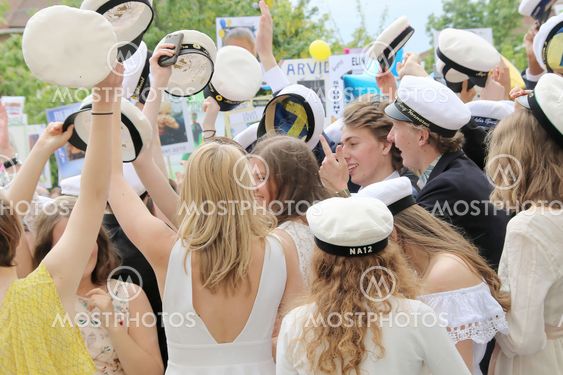 Happy teenagers raising the graduation cap celebrating...
