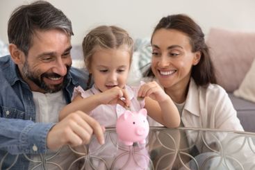Happy parents training little kid girl to save money