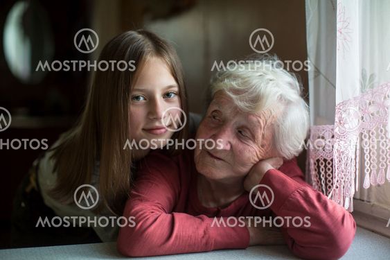 Little girl hugging elderly grandmother for a photo.