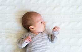 Cute newborn baby boy lying on bed, close up