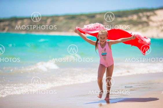 Little girl have fun with beach towel during tropical...