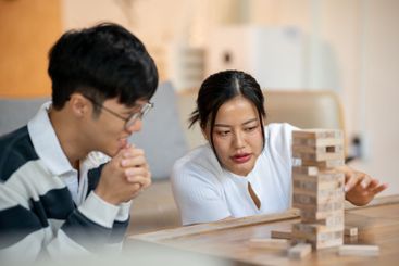 Two cheerful Asian friends enjoy playing Jenga together...