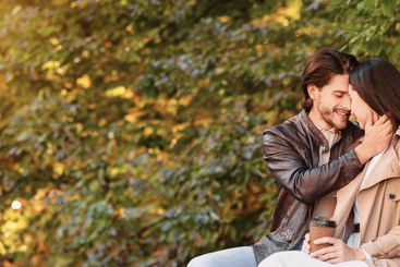 Beautiful romantic couple cuddling on bench at park