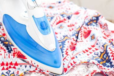 Iron on ironing board on light home interior background