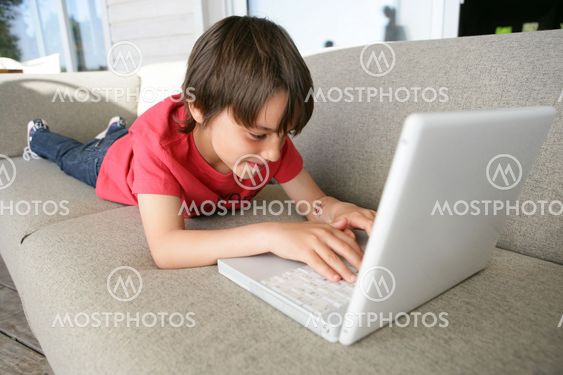 Boy using a laptop on the sofa