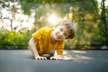 Little boy jumping on a trampoline in a backyard on warm...
