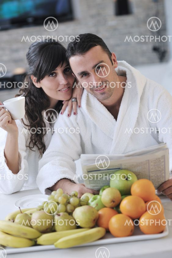 Happy couple reading the newspaper in the kitchen at breakfast