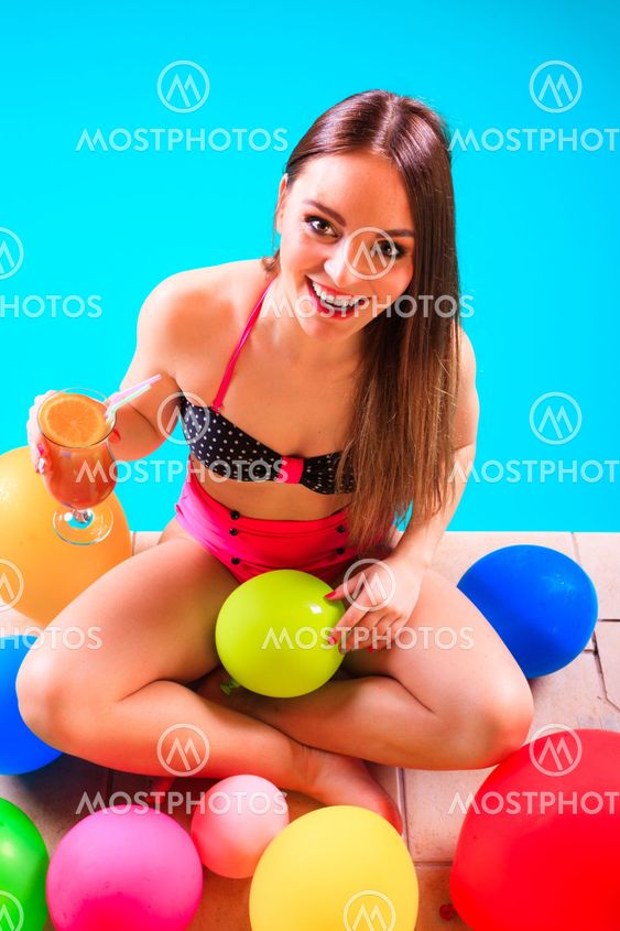 Happy woman with balloons and cocktail at poolside