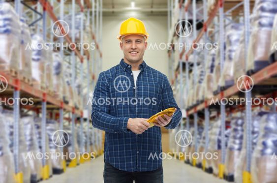 happy man in hardhat with gloves over warehouse
